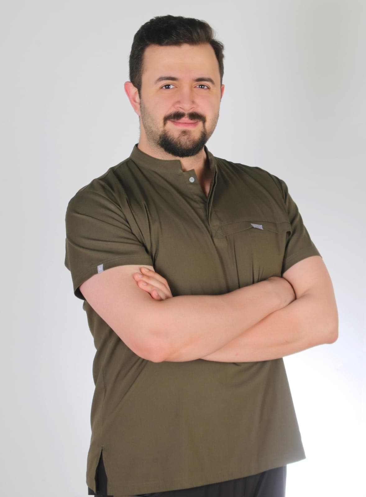 Dt. Akın Türköz, kolları önde bağlı, haki klinik forması içinde